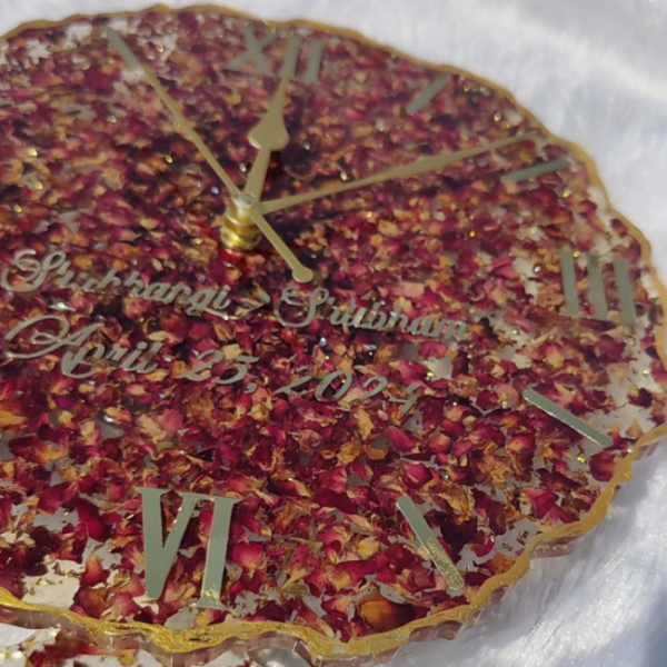 Decorative clock with rose petals and gold accents on a white background