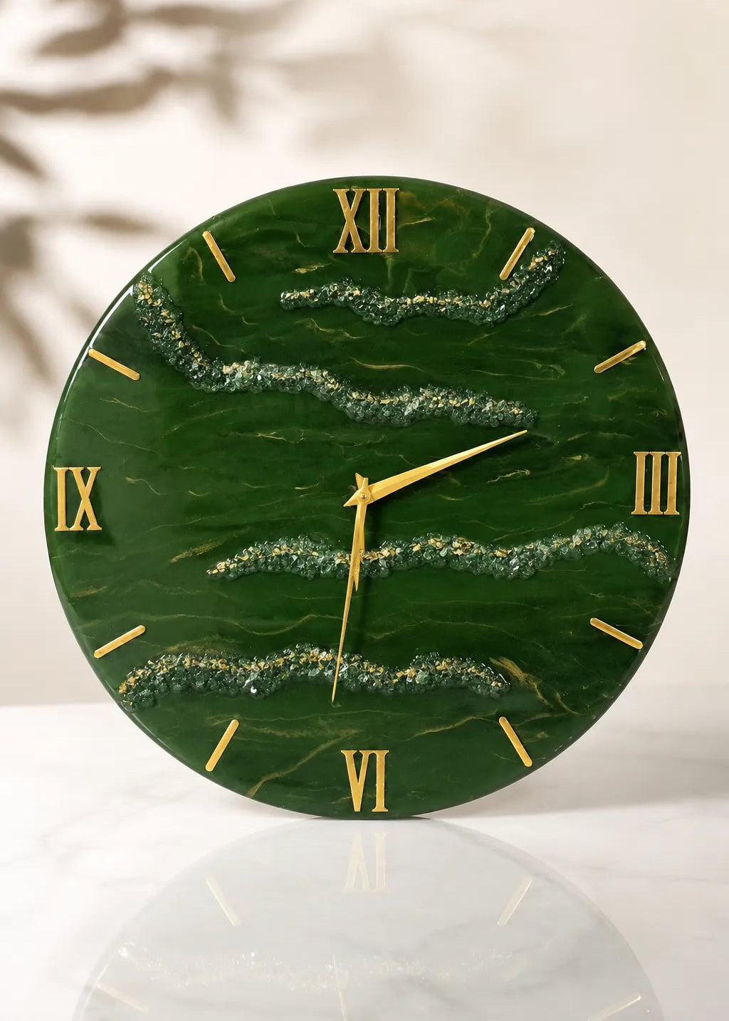 Green marble clock with gold Roman numerals on a white surface